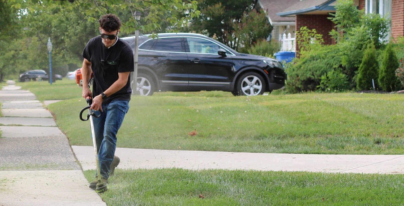 Jakub Miklus edging a lawn along a sidewalk