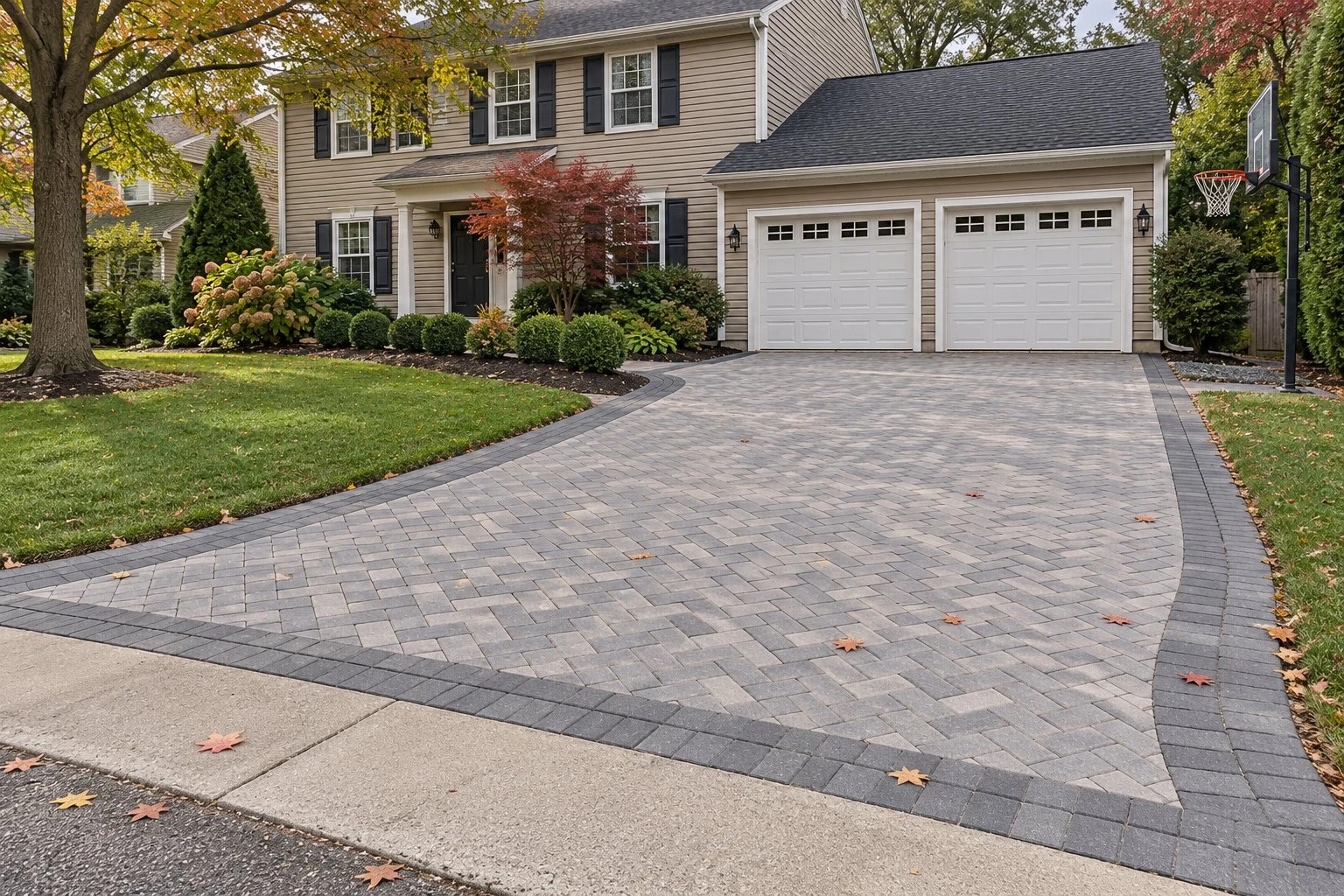 Grey herringbone paver driveway with a charcoal border in front of a two-car garage
